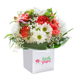 Jubilant and heart-warming, this bouquet overflows with colour, expertly positioned in a sleek white gift bag-ideal for gifting in Lower Clapton or sending a smile to a neighbour off Downs Road. The focal point is a bed of lush coral and crimson carnations, their petals finely ruffled and glowing softly beneath gentle light. Interlaced throughout, white daisies with vibrant yellow-green centers radiate cheerfulness-recalling wild blooms picked from the edges of Hackney Marshes. Wisps of baby's breath infuse a cloud-like softness, while a handful of purple-tinged buds peek out on the left, hinting at the bouquet's evolving beauty. All are enfolded by a ring of fresh, glossy green leaves, providing a deep, verdant backdrop that accentuates the arrangement's brilliant hues. The sturdy white ribbon handles indicate this bouquet's readiness for hand delivery or spontaneous celebration. Every element-arranged with care by local experts-is illuminated against a clean, pure white background, imbuing the flowers with a sense of optimism and sincerity. Perfect for birthdays, fresh starts, or simply lighting up a grey day, this bouquet captures the creative, welcoming spirit of Lower Clapton in every petal.